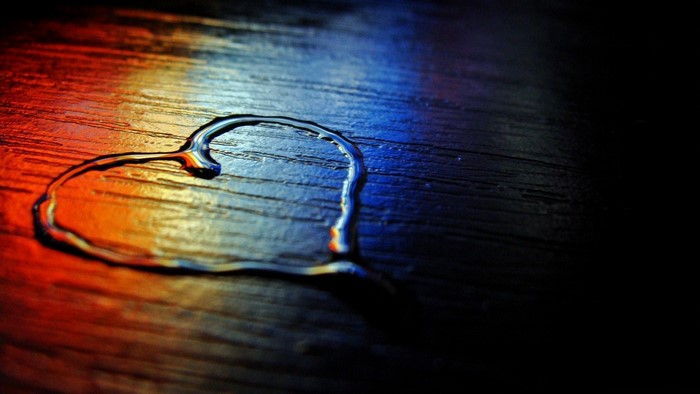 Heart shape made of water on a wooden surface