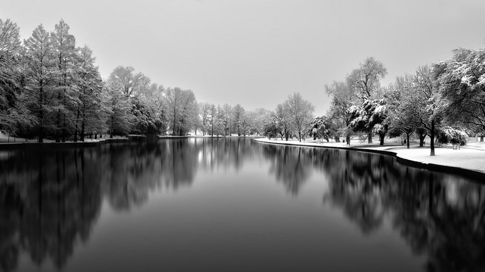Winter lake with snow-covered trees and reflections