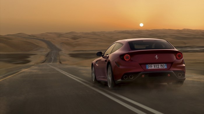 Ferrari driving on a desert road at sunset