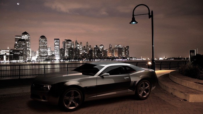 Chevrolet Camaro parked by a city skyline at night