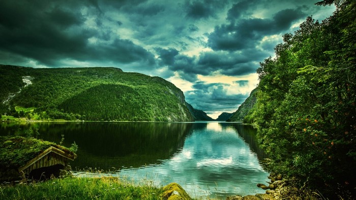 Lake between green mountains under cloudy sky