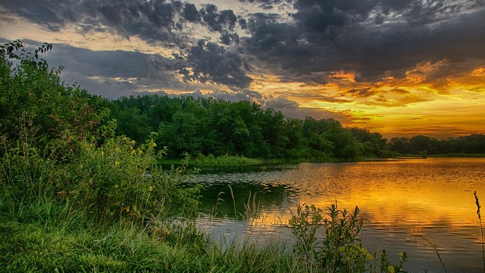 Sunset over a lake with trees and clouds