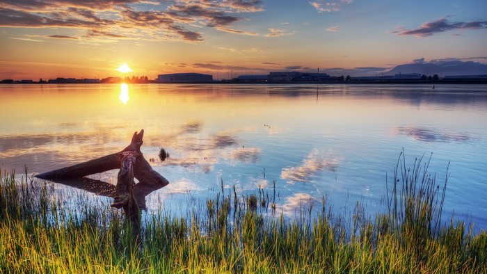 Sunset over water with industrial buildings