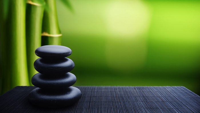 Zen stones stacked on a bamboo mat with bamboo stalks