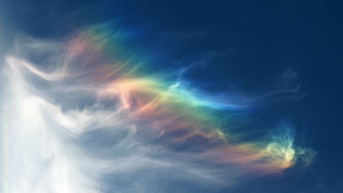 Rainbow spectrum in wispy clouds against a dark blue sky
