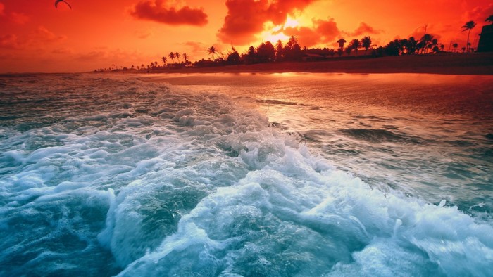Sunset over the ocean with waves and kite surfer
