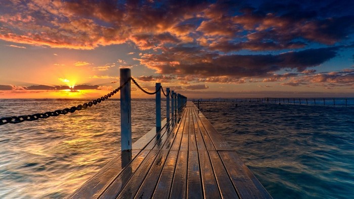 Sunset over the ocean with a wooden pier