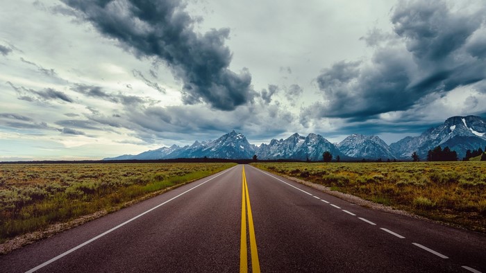 Straight Road Towards Mountains Under Cloudy Sky