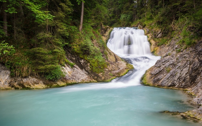 Waterfall cascading into a turquoise pool in a forest