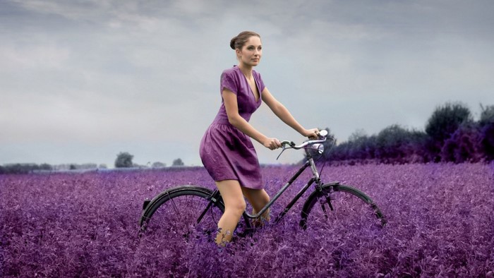 Woman riding a bicycle in a purple field