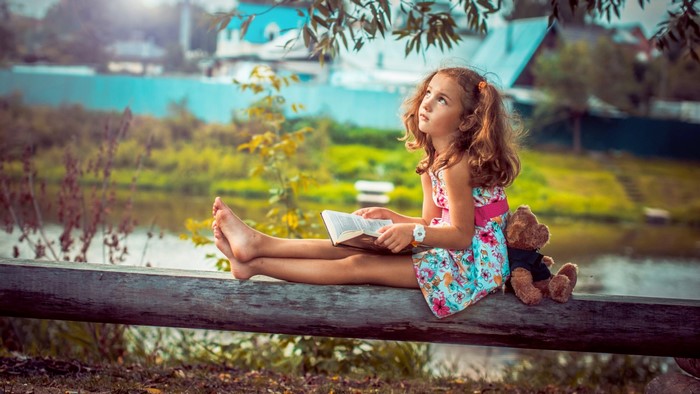 Girl reading a book with a teddy bear