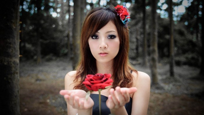 Girl with a red rose in a forest