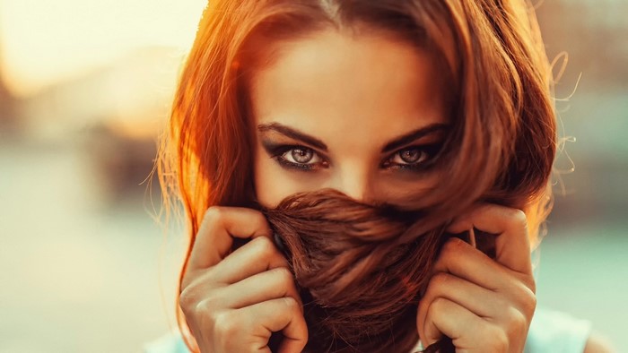 Redhead woman with beautiful eyes hiding face with hair