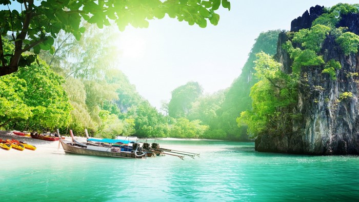 Tropical beach with longtail boats and kayaks