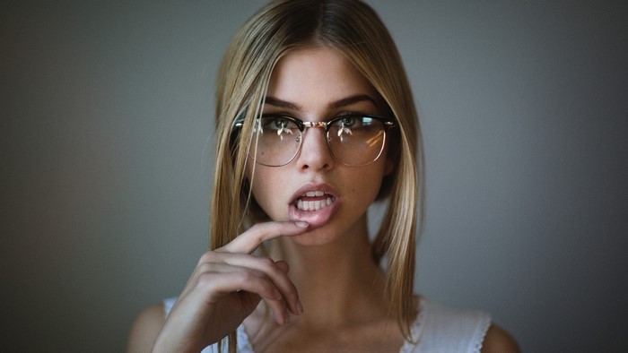 Blonde girl with glasses biting lip