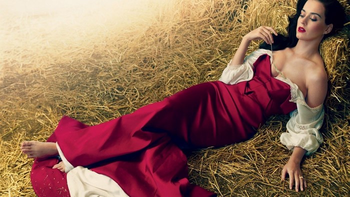 Katy Perry in a red dress lying on hay