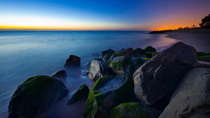 Sunrise over the ocean with rocks on the shore