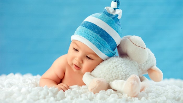 Baby in blue striped hat with sheep toy
