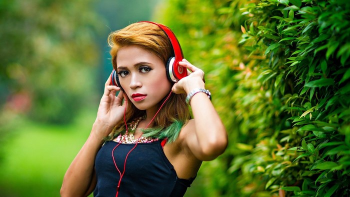 Girl with red Beats headphones in a garden
