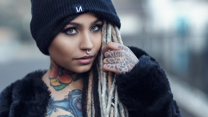 Woman with tattoos and nose rings wearing a beanie