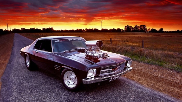 Customized muscle car with supercharger at sunset