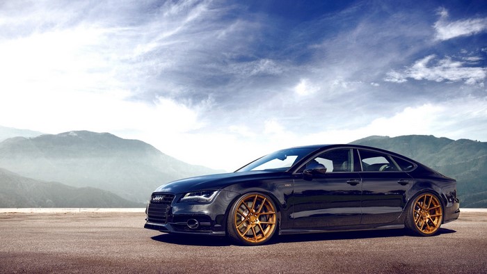 Black Audi A7 with gold rims on a road