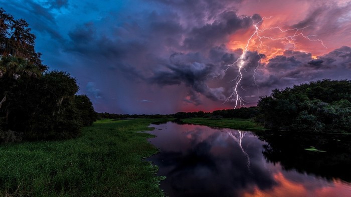 Thunderstorm over a river with lightning strike