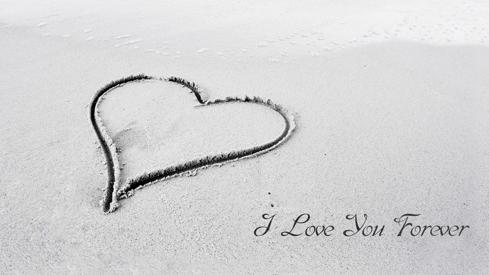 Heart drawn in sand with text