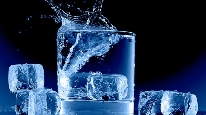 Ice cubes splashing into a glass of water