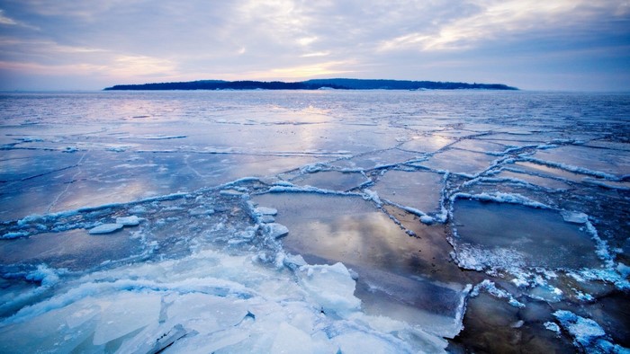 Ice floes on a body of water with an island in the distance