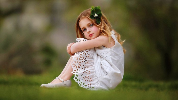 Cute child in a white dress with a flower in her hair