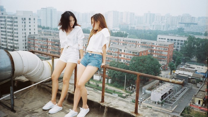 Two young women on a rooftop overlooking a city