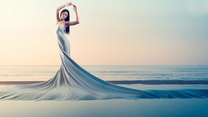 Woman in flowing dress on beach at sunset