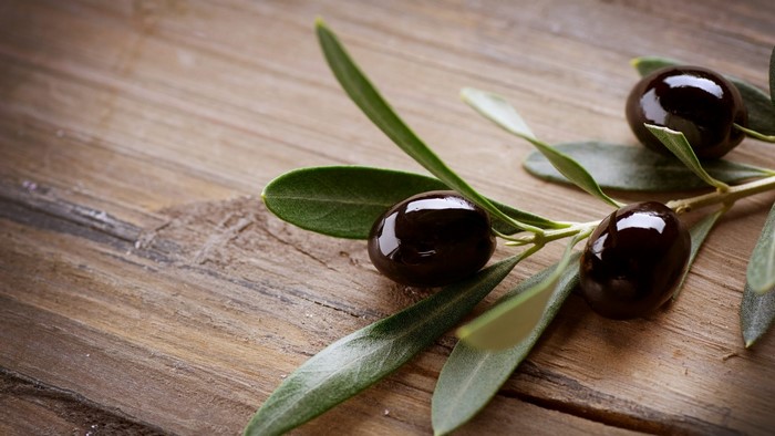 Olive branch with black olives on wooden surface
