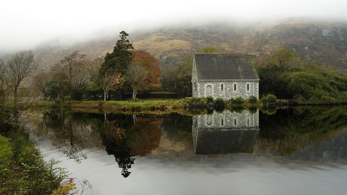 Stone building by a lake with misty mountains