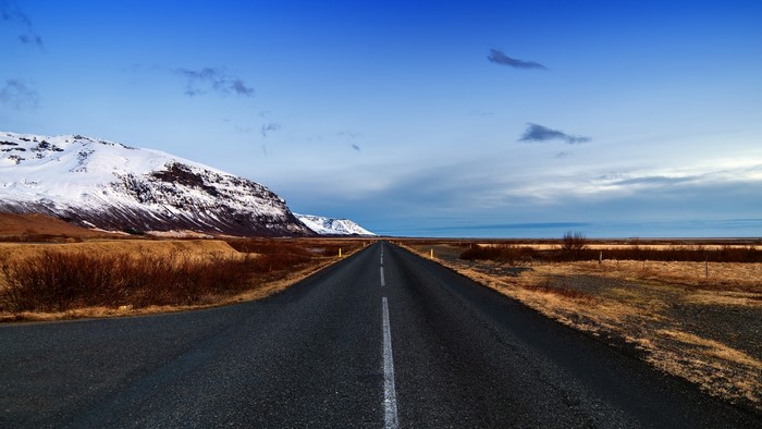 Road through Icelandic landscape with snow-capped mountains