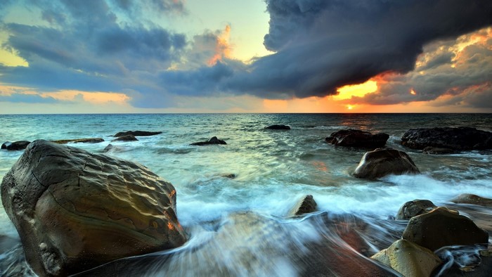 Ocean waves crashing on rocks at sunset