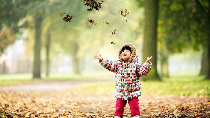 Child throwing leaves in the air
