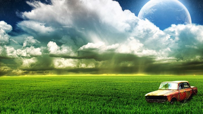 Old car in a field under a large moon and clouds
