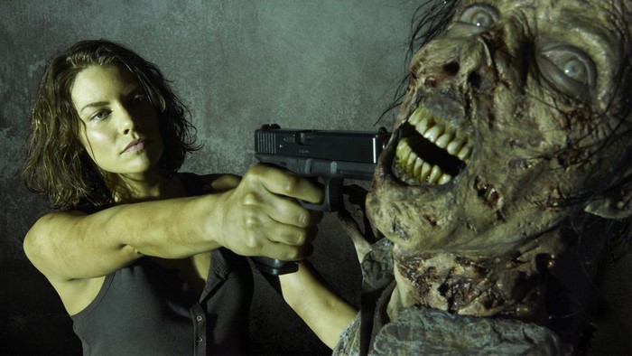 Lauren Cohan as Maggie from The Walking Dead aiming a gun at a zombie