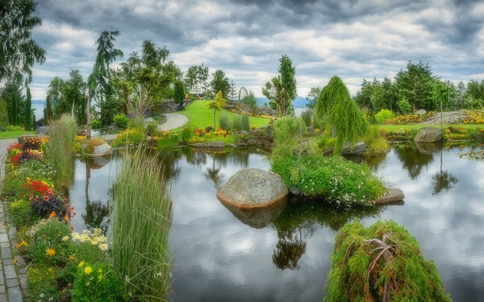 A tranquil garden pond with colorful flowers and trees