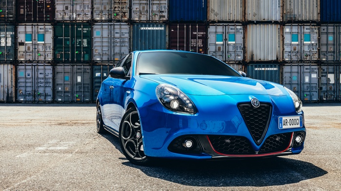 Blue Alfa Romeo Giulietta Quadrifoglio Verde parked by shipping containers