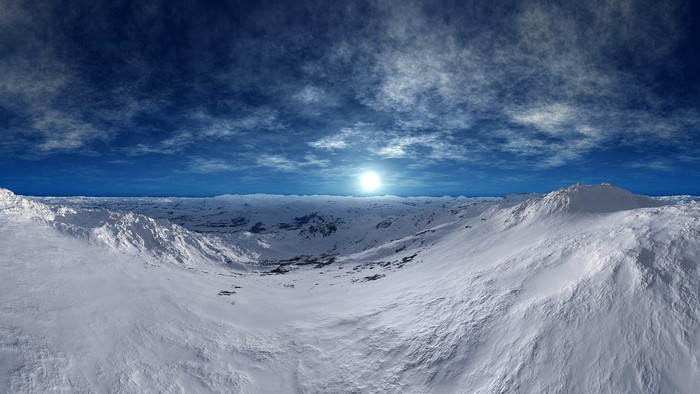Snowy Mountains Under a Cloudy Sky with a Bright Sun