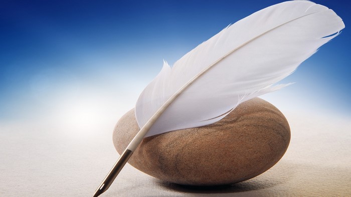 White feather quill pen on a stone