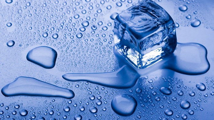 Ice cube melting with water drops