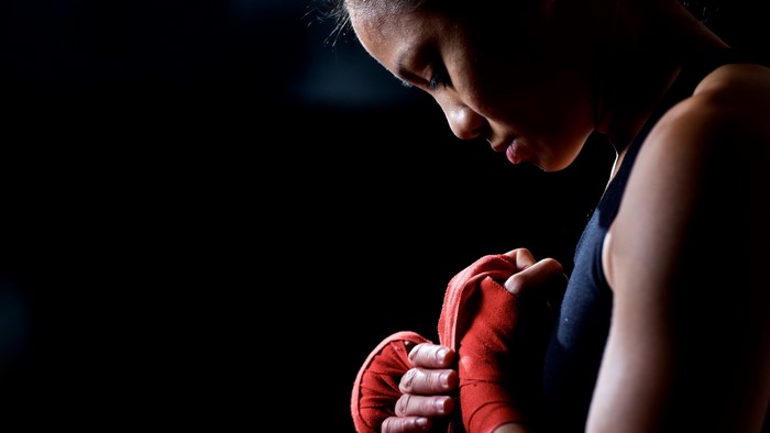 Woman wrapping hands with red boxing tape