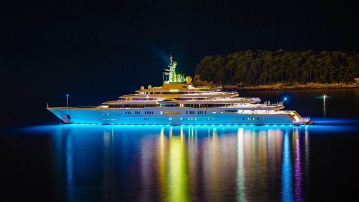 Luxury yacht illuminated at night with colorful lights