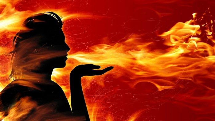 Silhouette of a woman blowing fire
