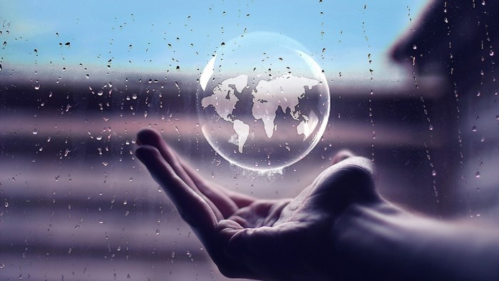 World map in a bubble over a hand