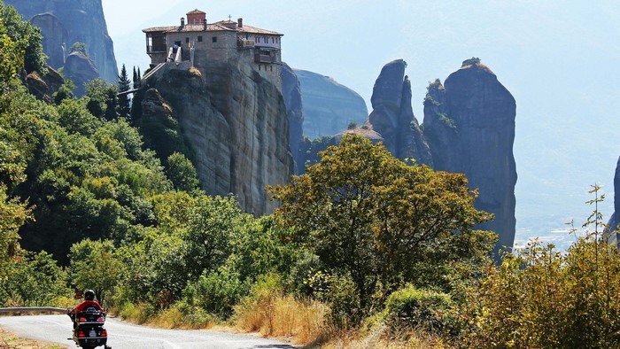 Monastery on a cliff in Meteora, Greece with a motorcyclist